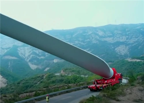 Wind-turbine blade on a trailer along a mountain road
