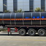 Dark cylindrical tanker trailer outside a workshop