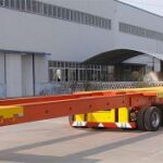 Red flatbed semi-trailer outside a workshop