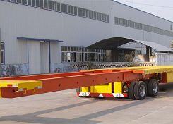 Red flatbed semi-trailer outside a workshop
