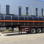 Side view of a dark tanker trailer outside a workshop