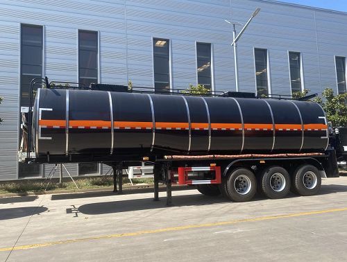 Side view of a dark tanker trailer outside a workshop